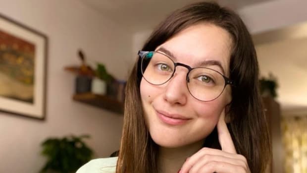 A woman with glasses smiling into the camera.