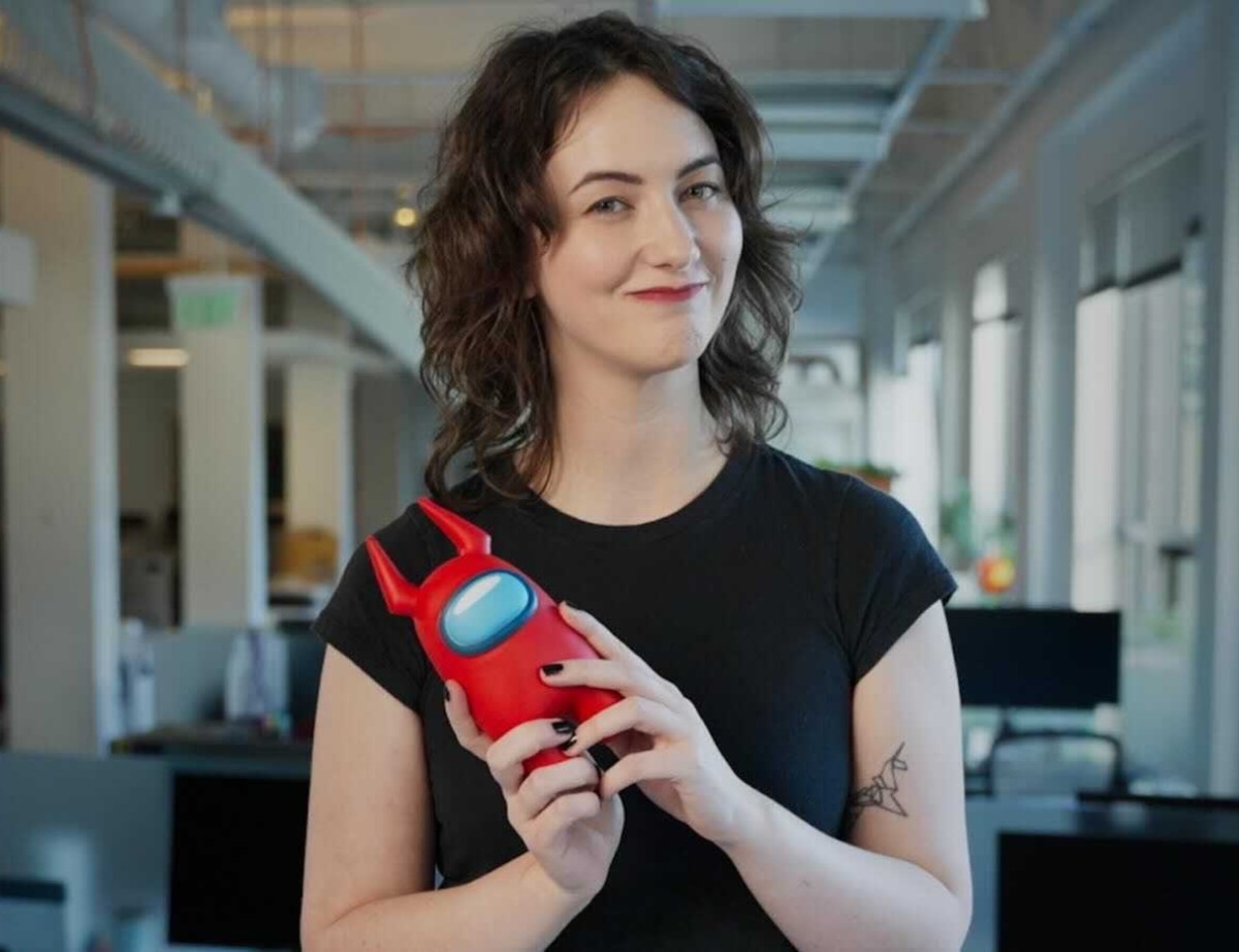 A women in a black shirt holding up a plushie from a character of the video game Among Us.